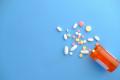 Prescription medication bottle with assorted pills on a blue background representing medication management and addiction treatment