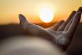 Open hand reaching toward a sunrise, symbolizing hope, healing, recovery, and new beginnings