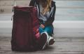 Person seated beside a travel bag symbolizing the decision to seek treatment, recovery support, and a new beginning
