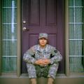Military service member seated outside a home, reflecting on the challenges of military life, stress, and recovery
