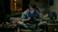 Man sitting alone at night staring at his phone at 3:17 a.m., showing unhealthy late-night AI use and digital dependence