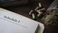 Capsules, powder, and a Schedule I document representing the federal crackdown on 7OH