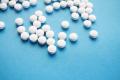 White prescription tablets scattered across a blue surface, representing medication use and substance dependence
