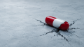 Cracked red and white capsule on fractured concrete representing mitragynine pseudoindoxyl (pseudo) drug risks and addiction dangers.