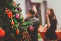 Decorated Christmas tree with holiday ornaments during a festive gathering in the background