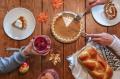 People sharing pie, bread, and drinks around a table during a communal meal