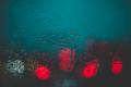 Blurred traffic lights seen through a rain-covered window, representing stress, uncertainty, and emotional challenges