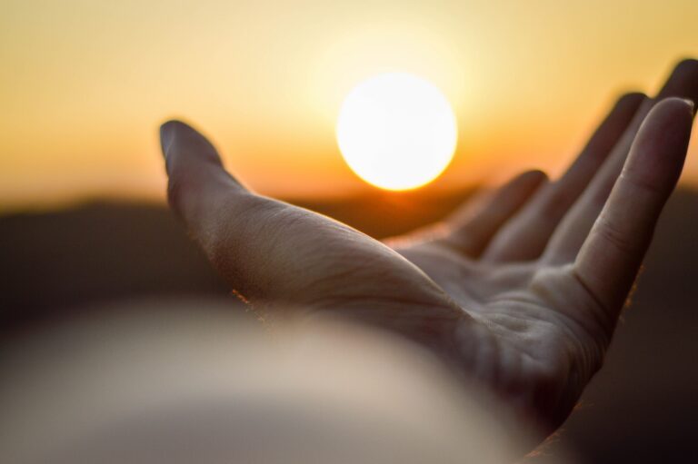 Open hand reaching toward a sunrise, symbolizing hope, healing, recovery, and new beginnings