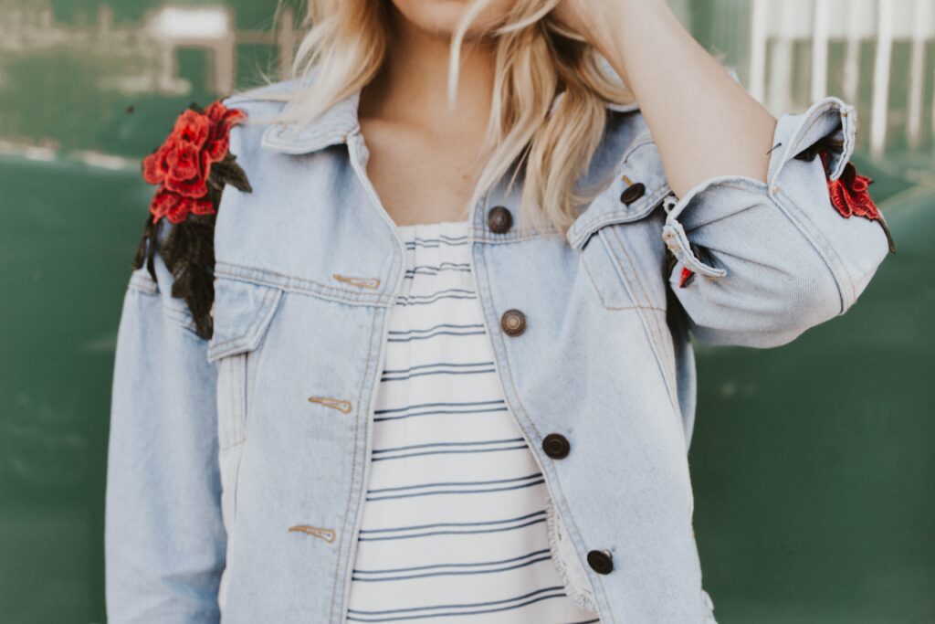 Person wearing a denim jacket with floral embroidery, representing self-expression, confidence, and personal identity