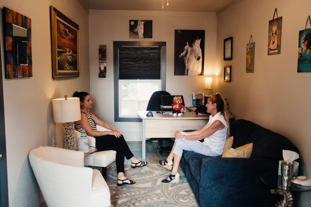 Two people engaged in a one-on-one counseling session in a comfortable therapy office