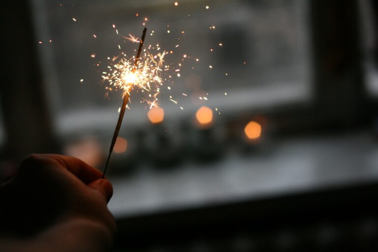 Hand holding a lit sparkler with bright sparks, symbolizing hope, recovery, and positive change