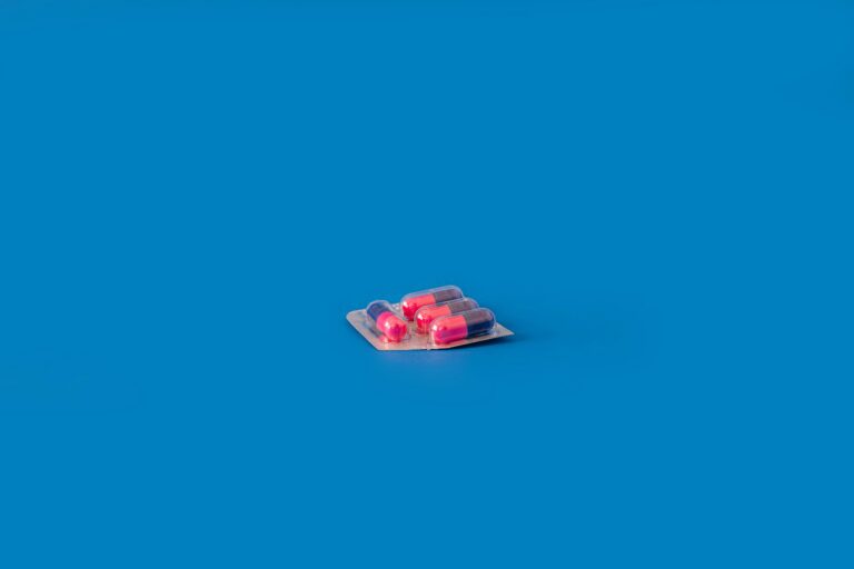 Blister pack containing prescription capsules on a blue background, representing medication-assisted treatment and substance use recovery