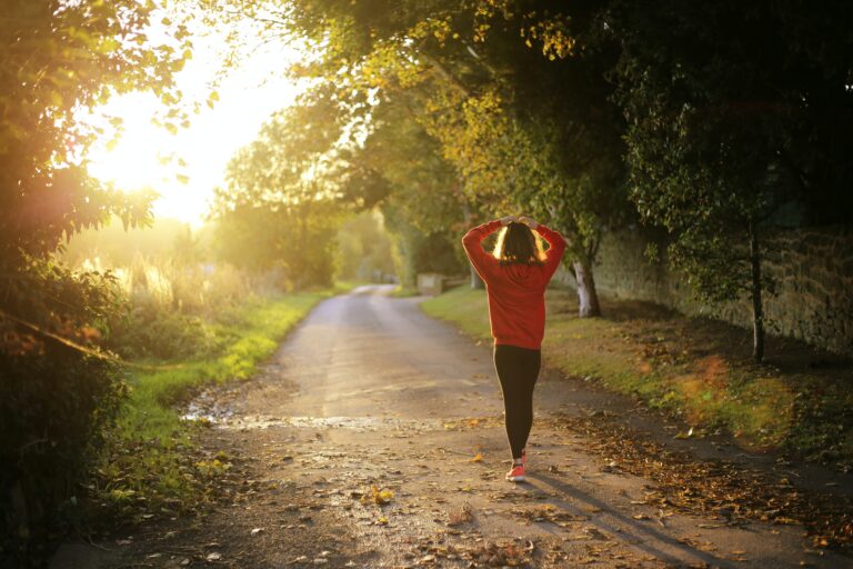 Person walking alone down a tree-lined path at sunrise, symbolizing recovery, healing, and personal growth