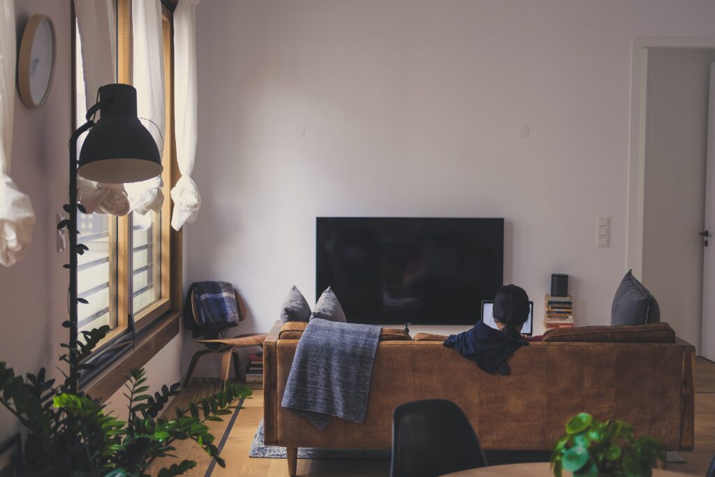 Person sitting alone in a quiet living room, representing solitude, reflection, mental health, and recovery at home