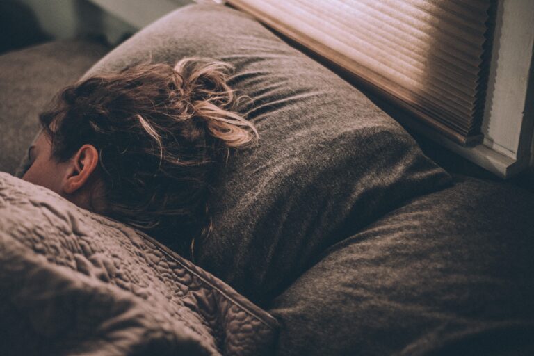 Person resting in bed under a blanket, illustrating sleep, rest, and recovery