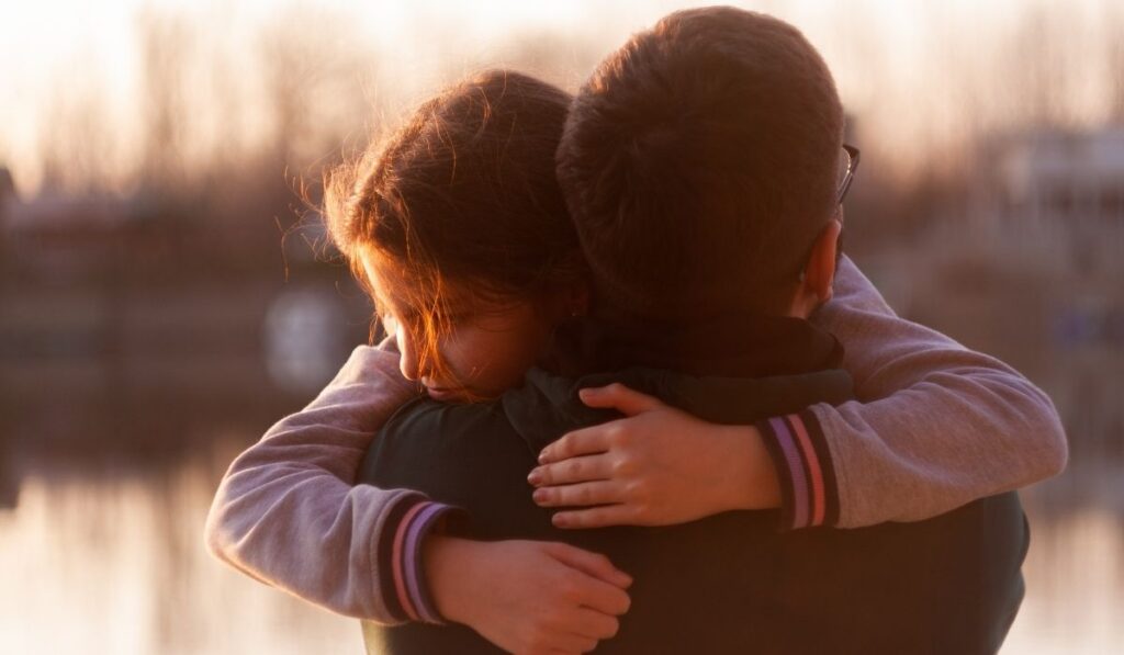 Two people embracing outdoors, offering comfort, support, and connection during a difficult time