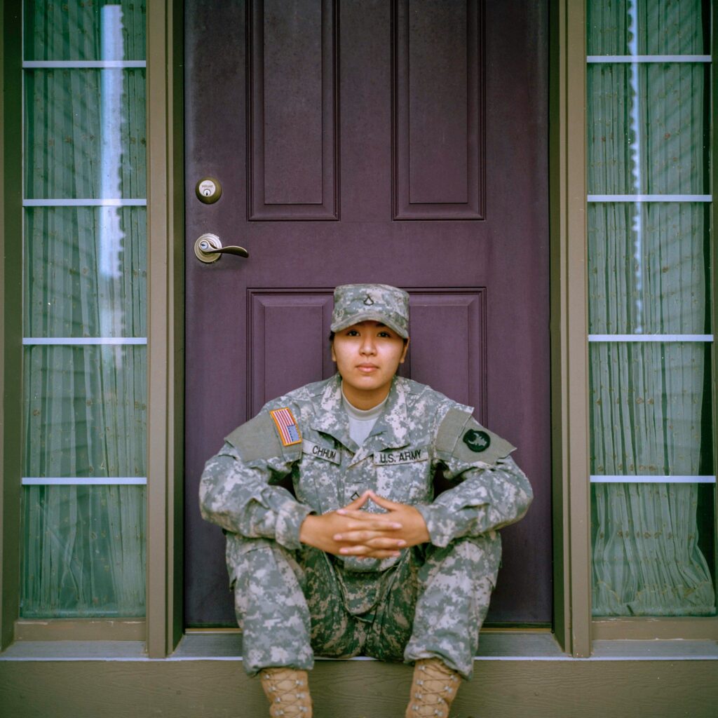 Military service member seated outside a home, reflecting on the challenges of military life, stress, and recovery