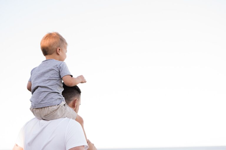 Father carrying a young child on his shoulders while walking outdoors