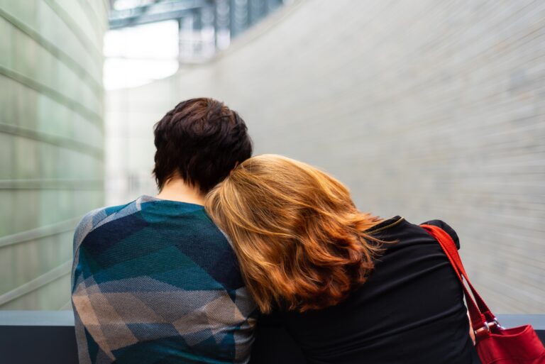 Two people leaning on each other for comfort and support, representing connection, healing, and recovery