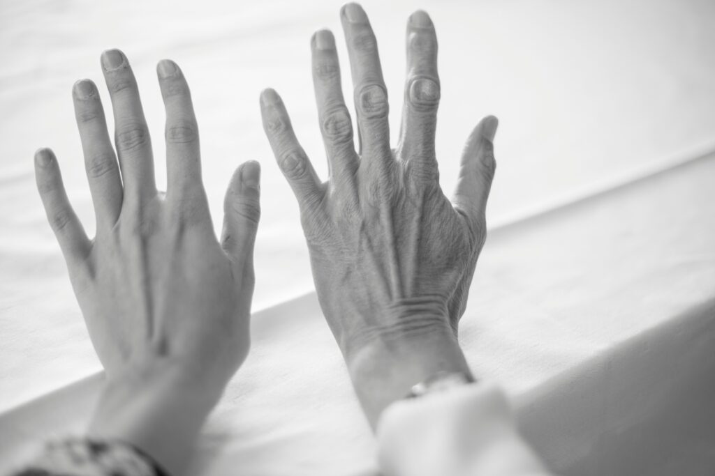 Two hands of different ages placed side by side, symbolizing aging, family connection, and generational relationships