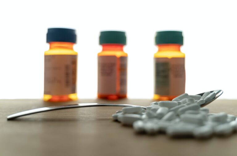 Prescription pill bottles and white tablets on a table, representing medication use and treatment