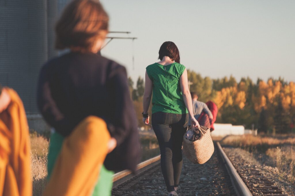 People walking along railroad tracks outdoors during a group activity, symbolizing personal growth, recovery, and moving forward