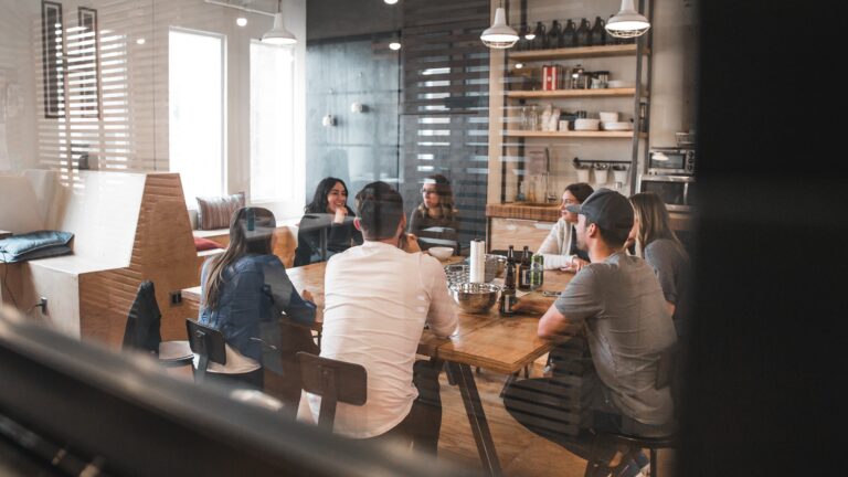 Group therapy session with participants gathered around a table discussing recovery, mental health, and personal growth