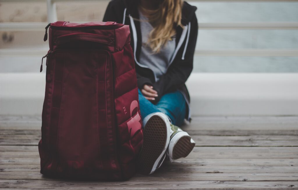 Person seated beside a travel bag symbolizing the decision to seek treatment, recovery support, and a new beginning