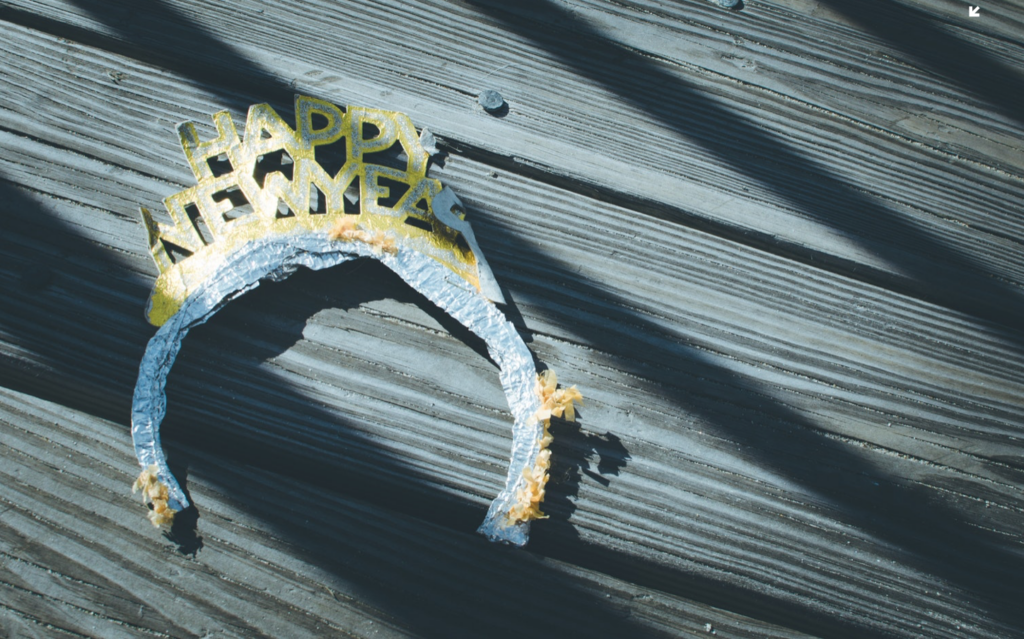 "Happy New Year" party headband resting on a wooden surface, symbolizing holiday celebrations, reflection, and recovery during festive seasons