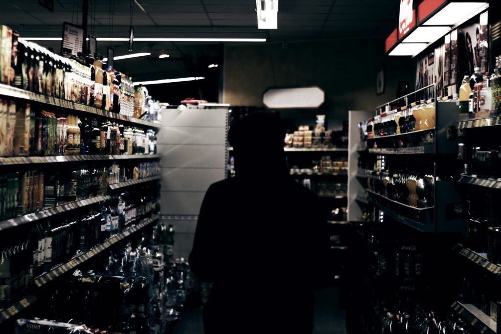 Person standing in a grocery store aisle surrounded by beverage and food shelves