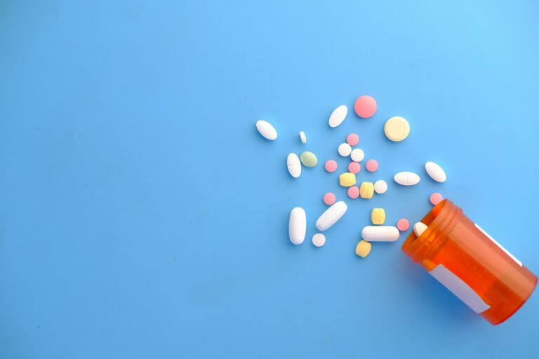 Prescription medication bottle with assorted pills on a blue background representing medication management and addiction treatment