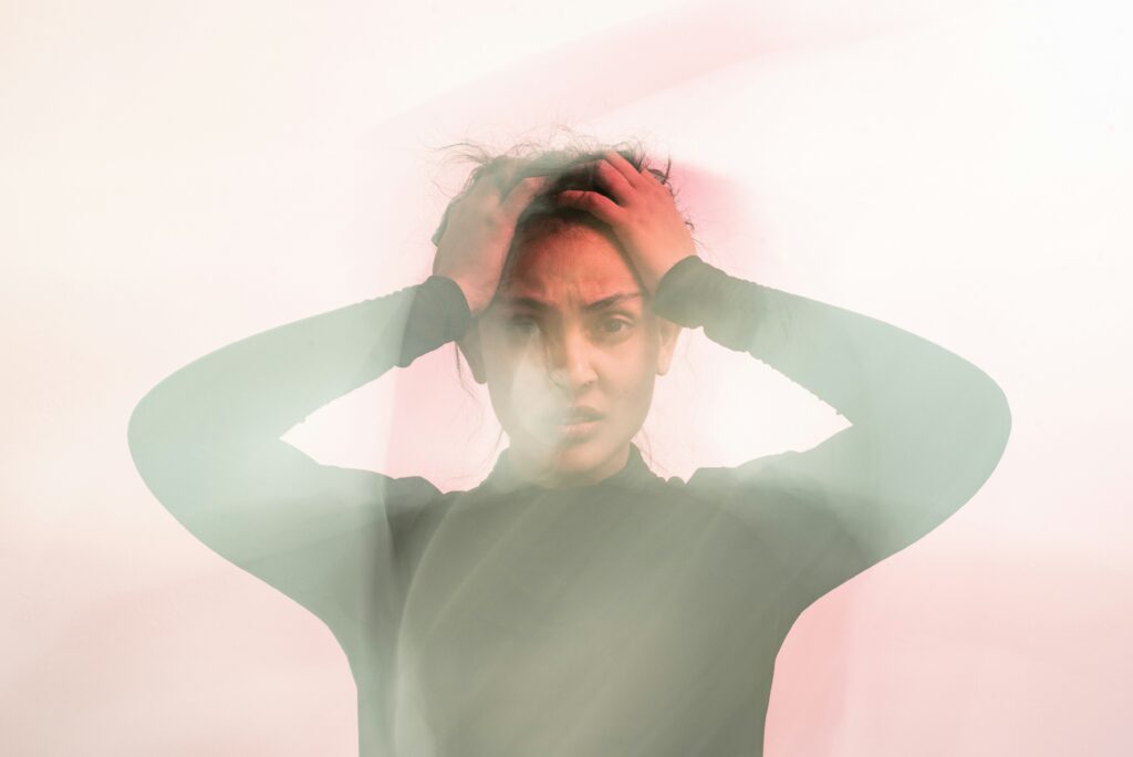 Person holding their head with a distressed expression, representing stress, anxiety, emotional overwhelm, and mental health challenges
