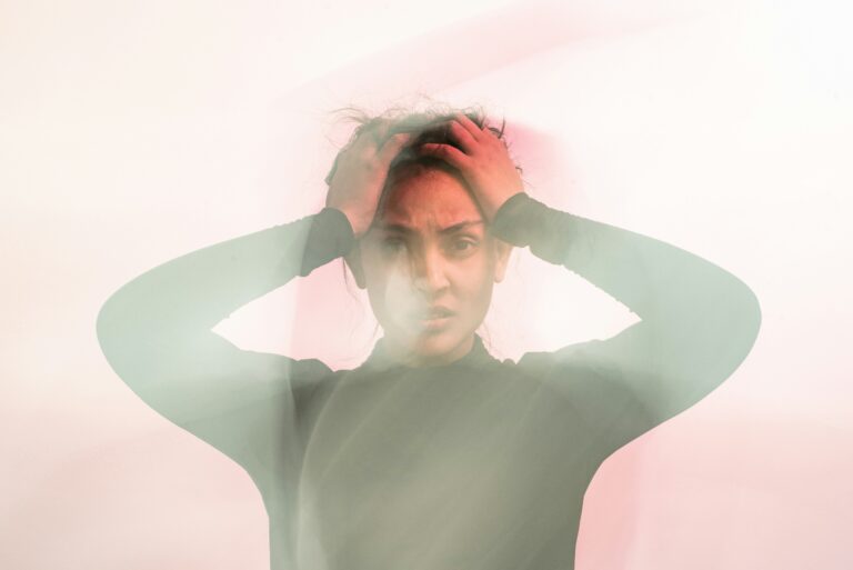 Person holding their head with a distressed expression, representing stress, anxiety, emotional overwhelm, and mental health challenges